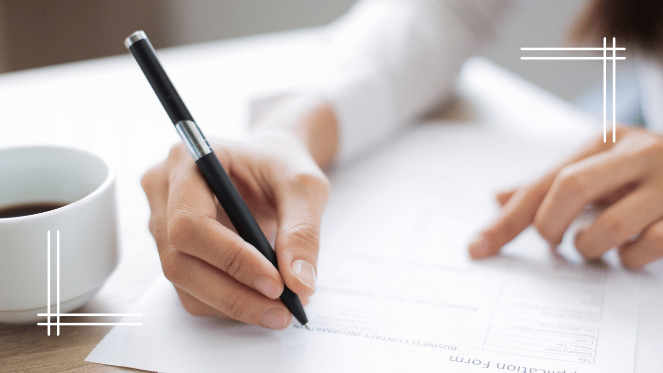 A person filling out a form with a pen, accompanied by a cup of coffee on the side